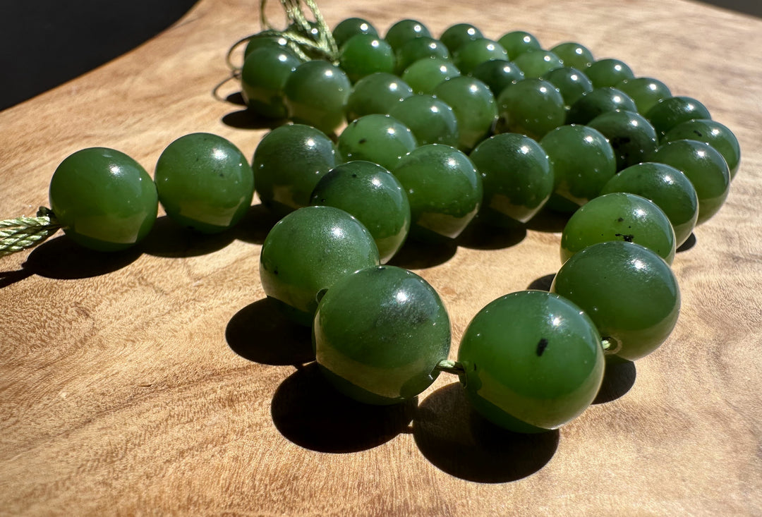 Green jade 10mm beads on a wooden surface with a dark background