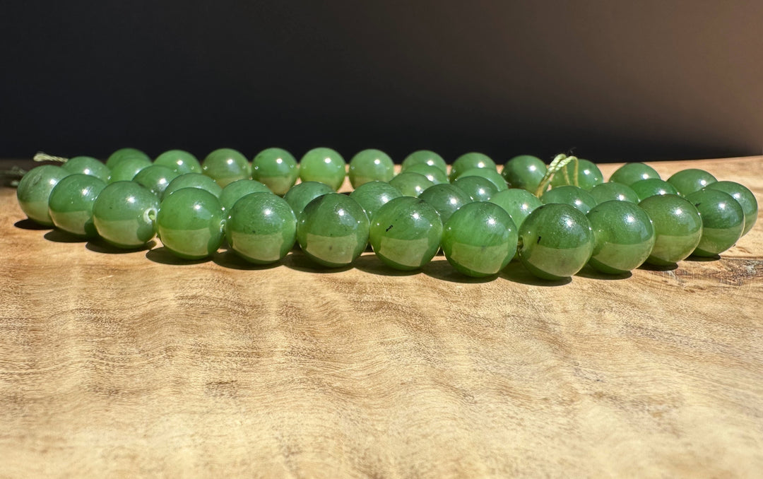 Green jade 10mm beads on a wooden surface with a dark background
