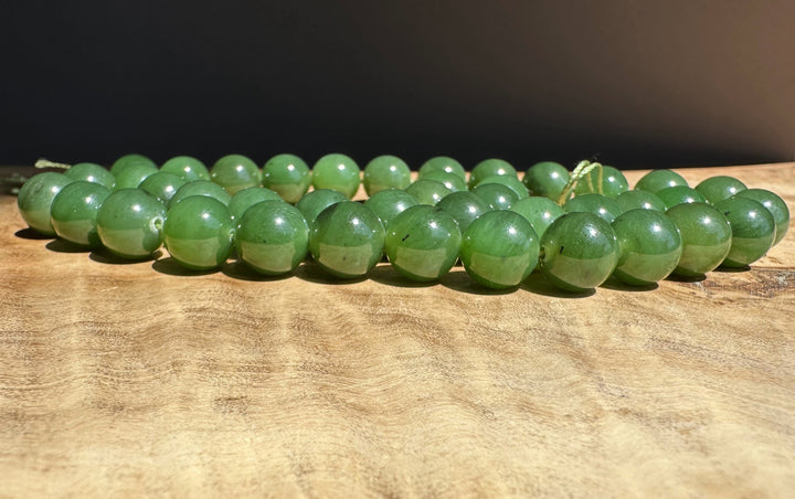 Green jade 10mm beads on a wooden surface with a dark background