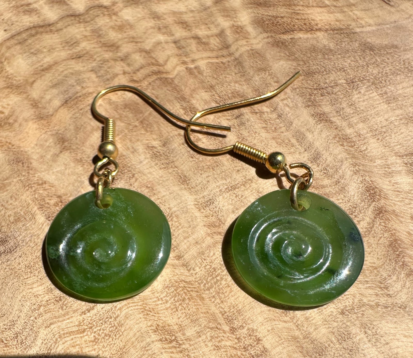Green spiral earrings on a wooden surface