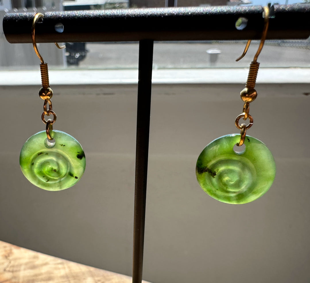 Green spiral earrings on a stand with a blurred background