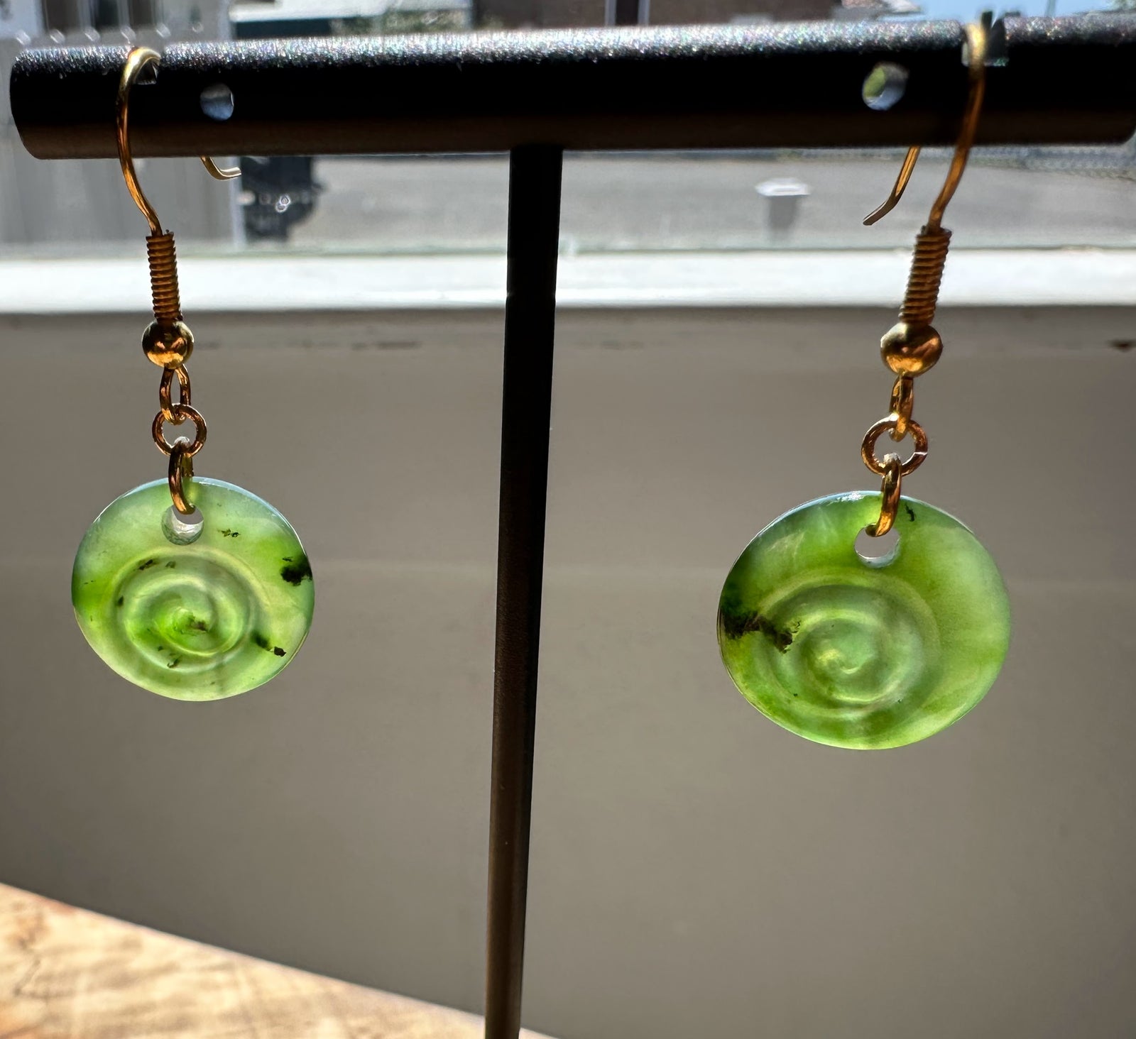 Green spiral earrings on a stand with a blurred background