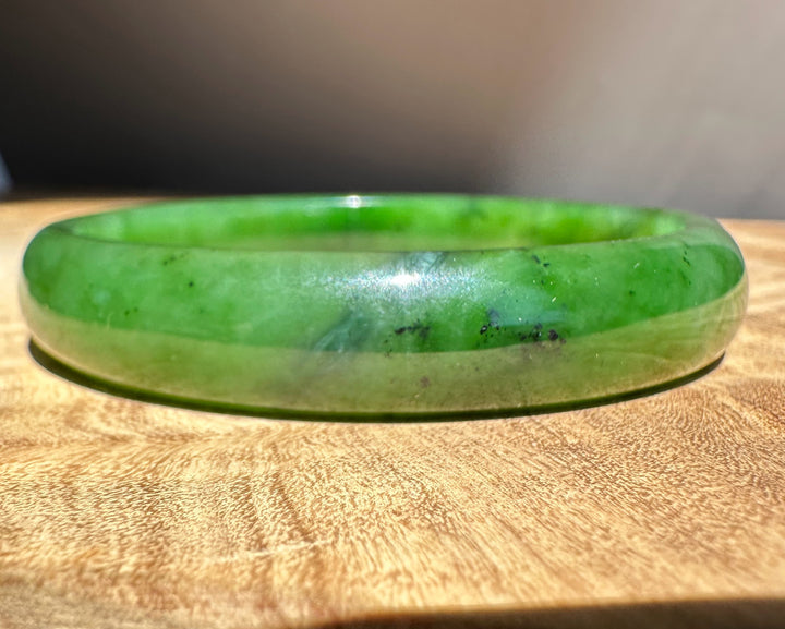 Green jade bracelet on a wooden surface with a blurred background