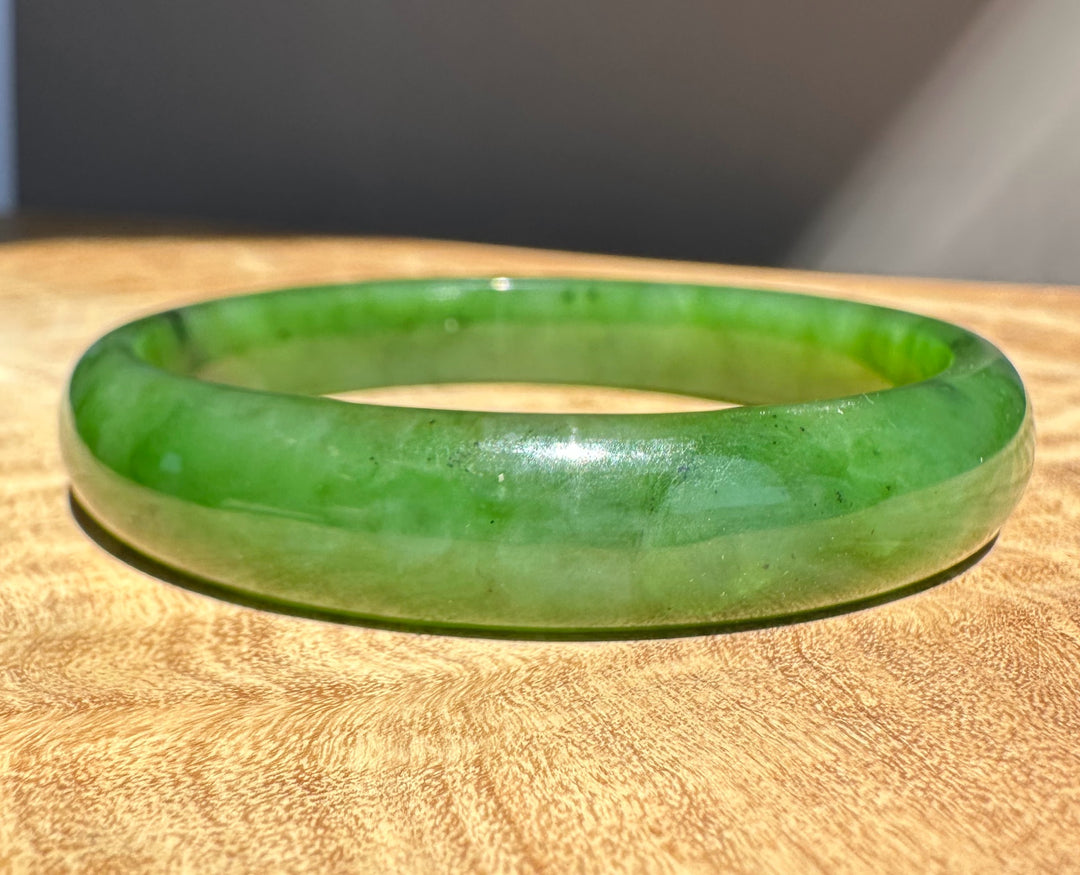 Green jade bracelet on a wooden surface with a neutral background