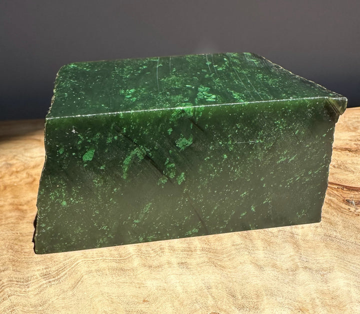Green jade block on a wooden surface with a dark background