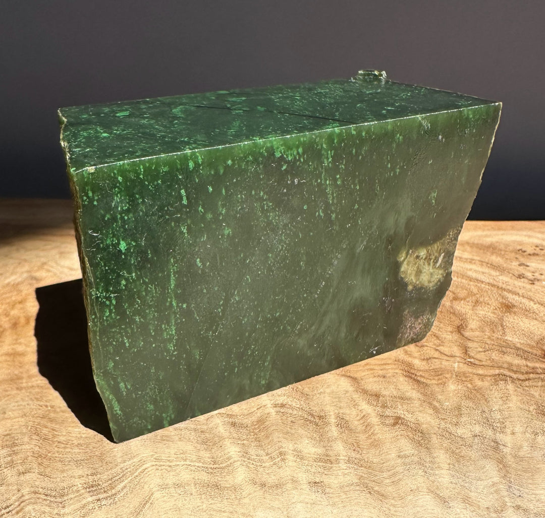 Green jade block on a wooden surface with a dark background