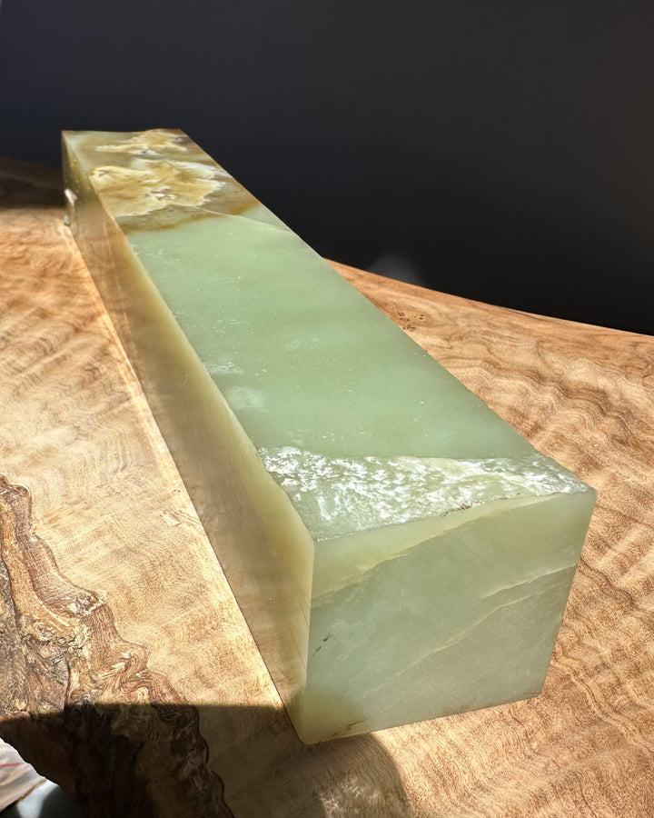 jade white green stone block on a wooden surface with a dark background