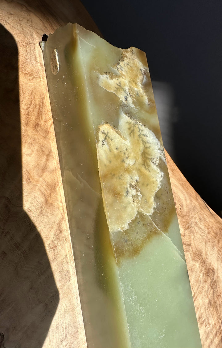 Greenish white stone with natural patterns on a wooden surface