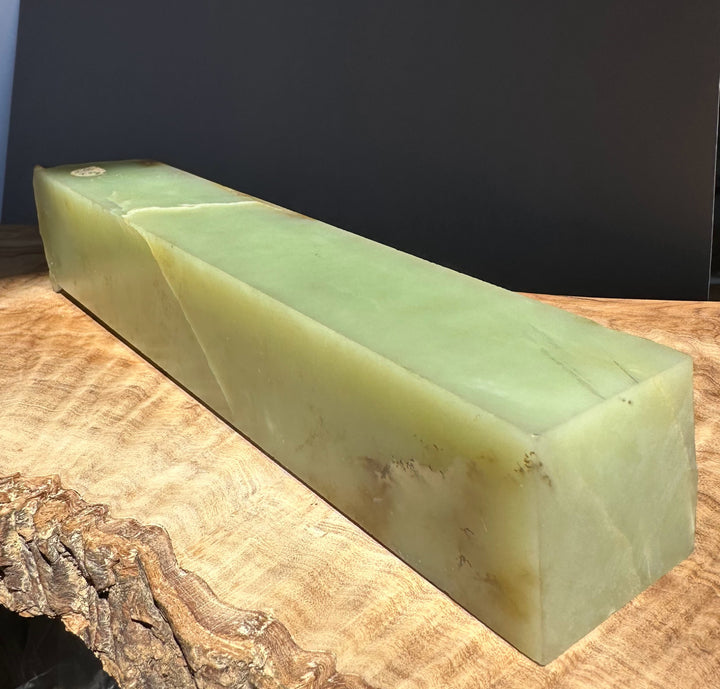 Green jade block on a wooden surface with a dark background