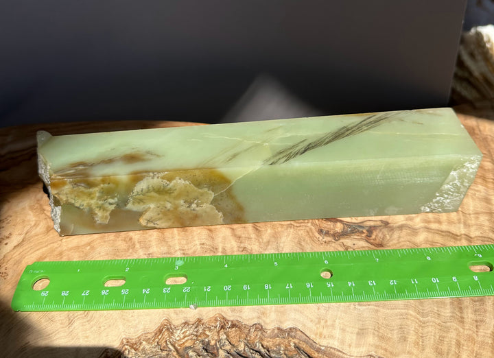 Jade green white rough on a wooden surface with a green ruler for scale.