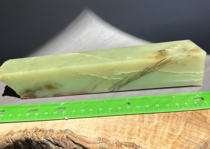 jade stone block with a ruler for scale on a wooden surface