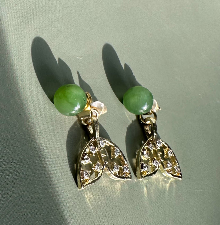 Whale tail earrings with green beads on top and crystal studded silver tails.