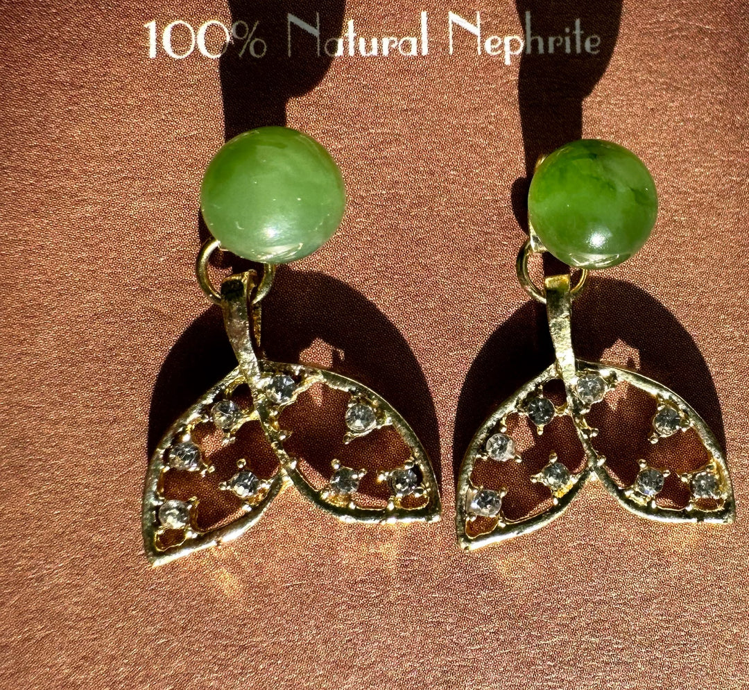 Pair of whale tail earrings on a brown burgundy backdrop with green nephrite beads and crystal tails