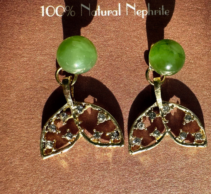 Pair of whale tail earrings on a brown burgundy backdrop with green nephrite beads and crystal tails