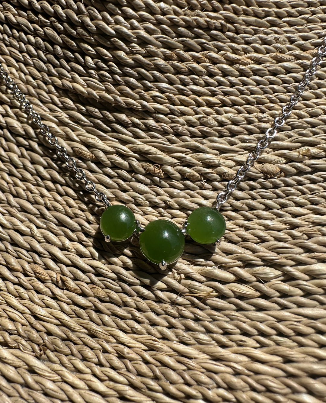 Necklace with green beads on a textured woven surface
