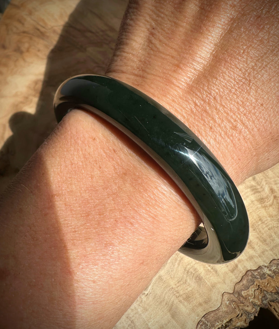 Dark Green bracelet on a wrist with a natural wood background