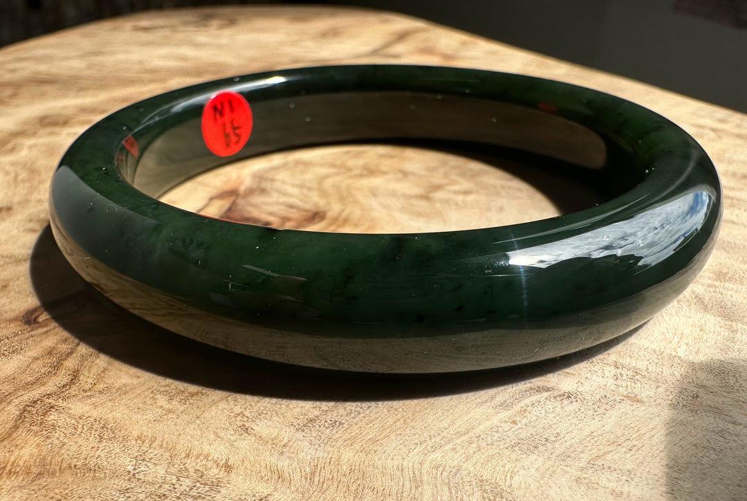 Green bangle on a wooden surface with a red label