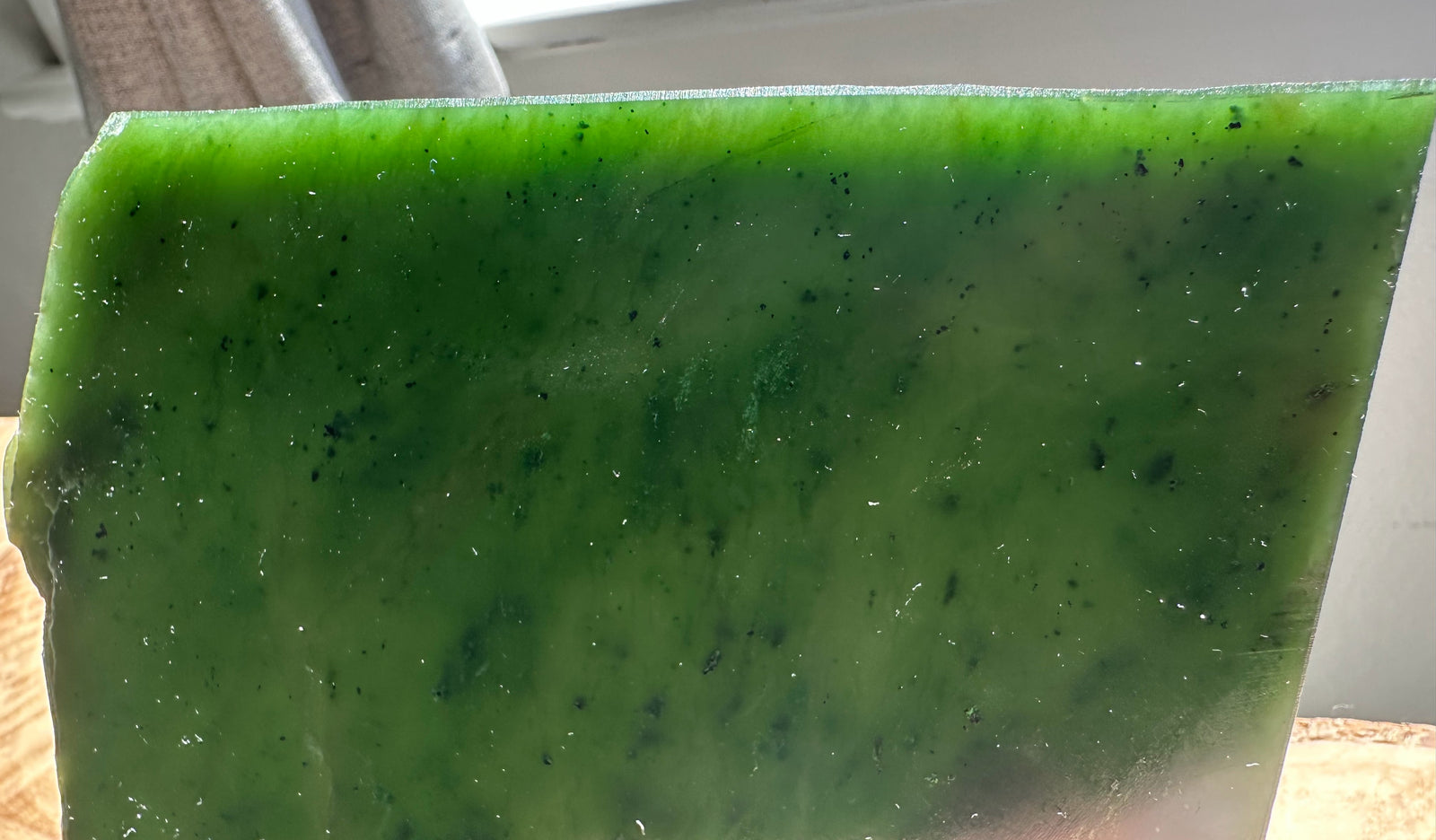 Edge view of a glossy green jade slab showing crisp edge and vibrant color