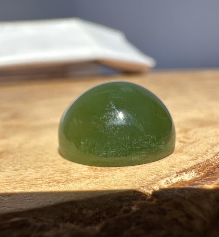 Green jade cats eye on a textured beige surface, blurred background