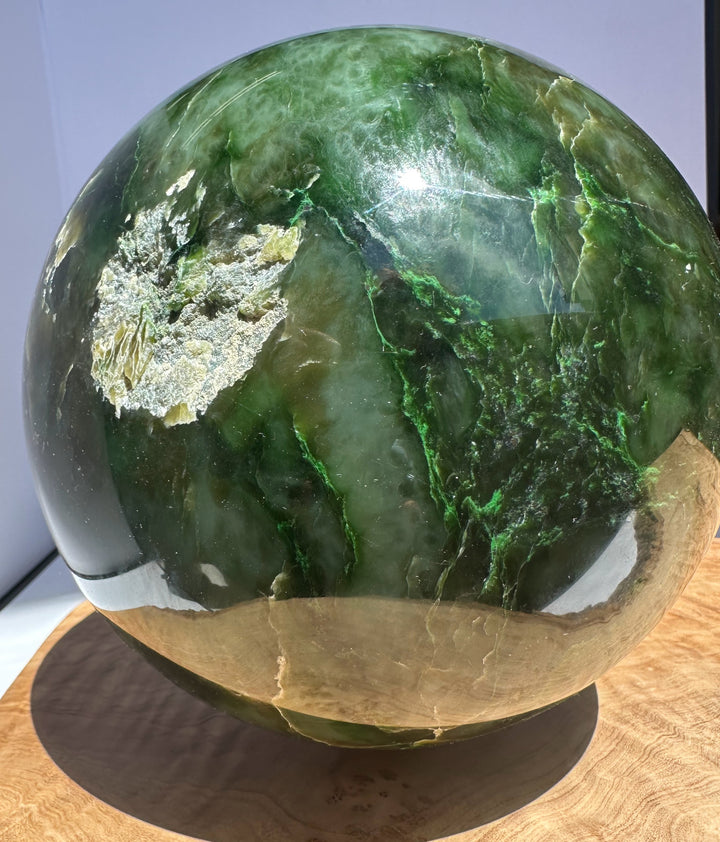 Side view of Polar Jade Sphere showing dark and light green bands and bright reflection on its surface
