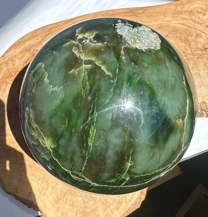 6 inch Polar Jade Sphere with dark green tones and white veining on a wooden display base