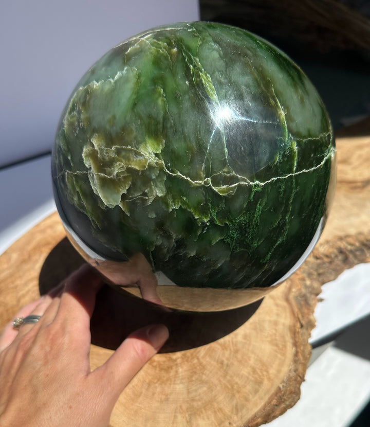 6 inch Polar Jade Sphere with green and pale veining resting on a wooden display base