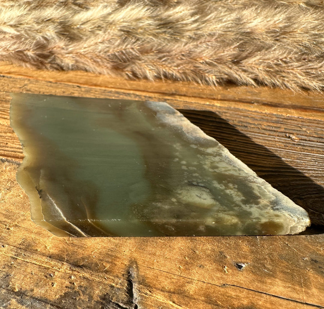 Wyoming Nephrite Slab 80g with smooth green gray surface on wood and fur backdrop