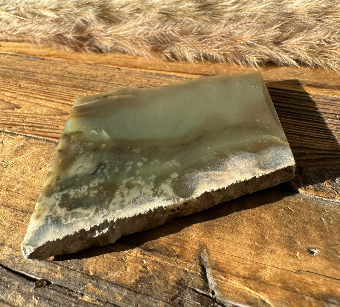 Wyoming Nephrite Slab 80g pale green surface and rough edge on wood