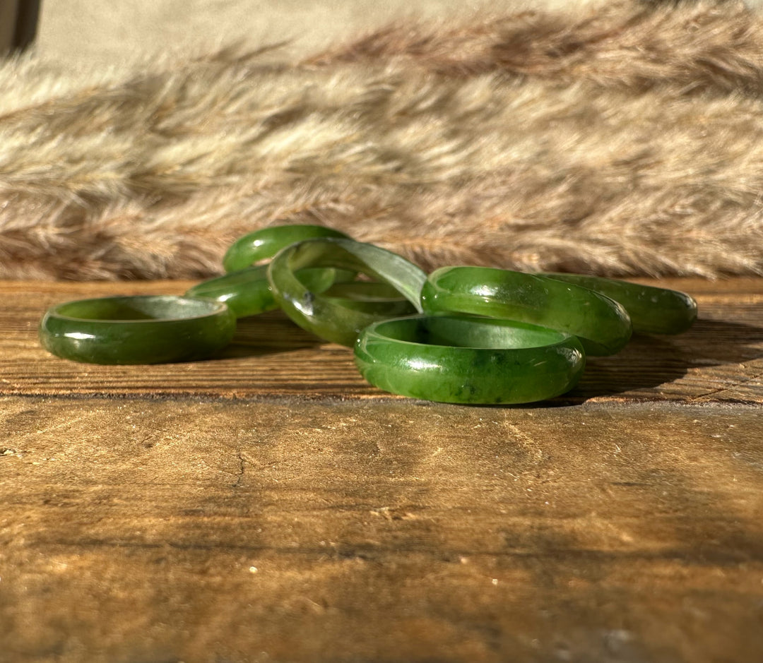 Close up of green jade band rings on a wooden surface with a soft fur backdrop