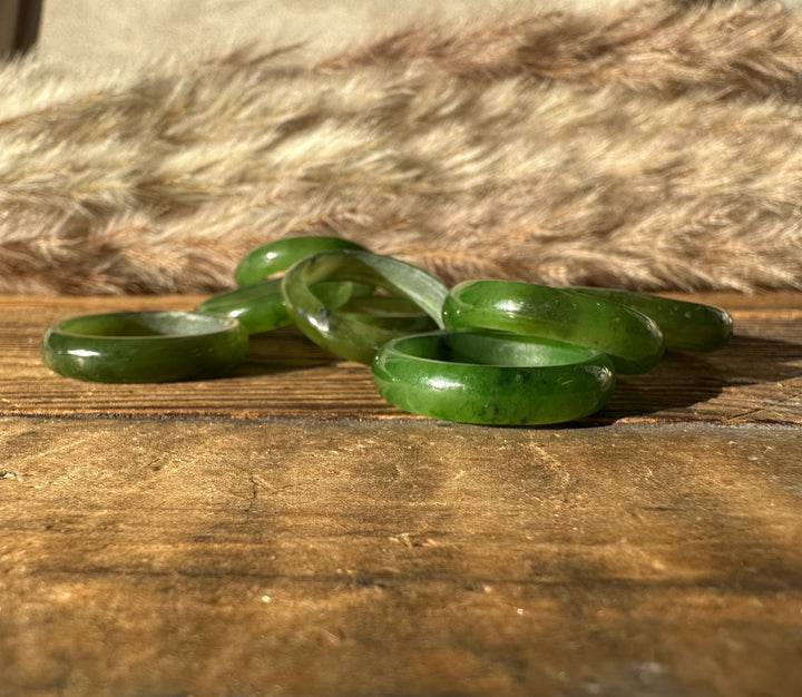 Close up of green jade band rings on a wooden surface with a soft fur backdrop