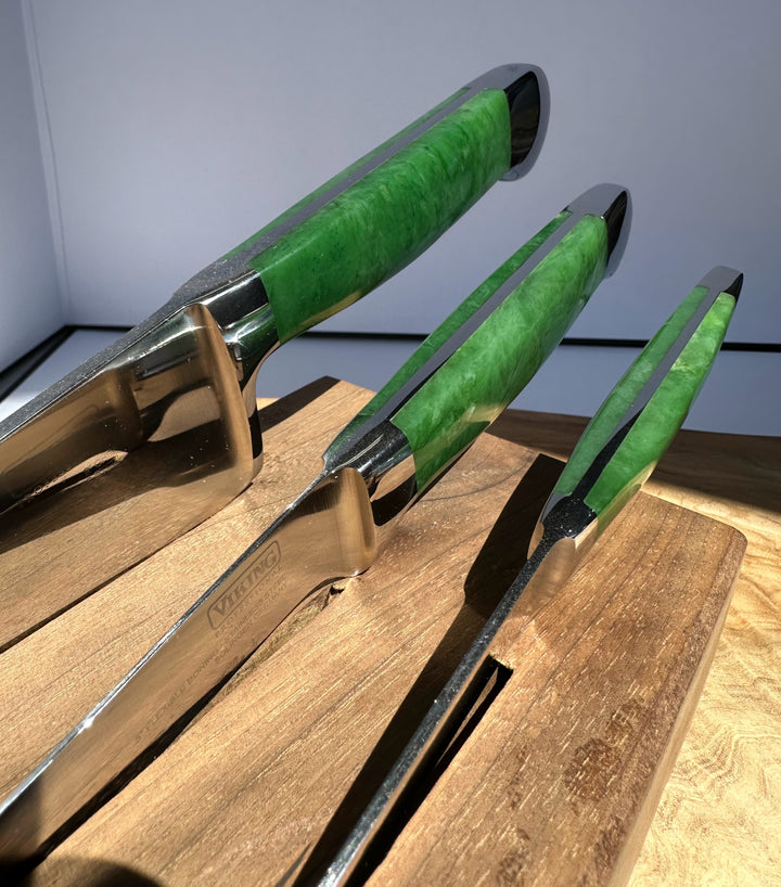 Three knives with green handles on a wooden surface.