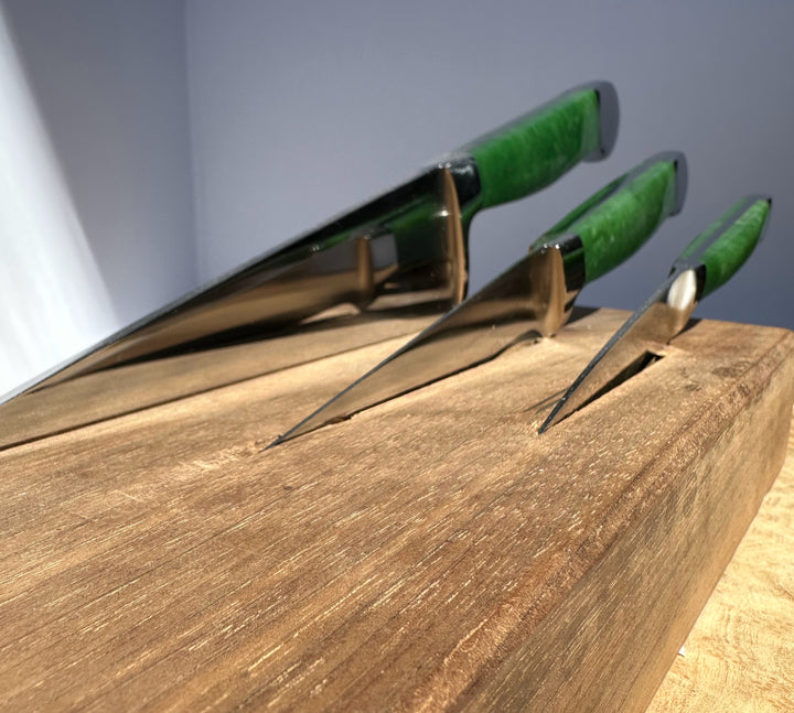 Three knives with green handles on a wooden surface