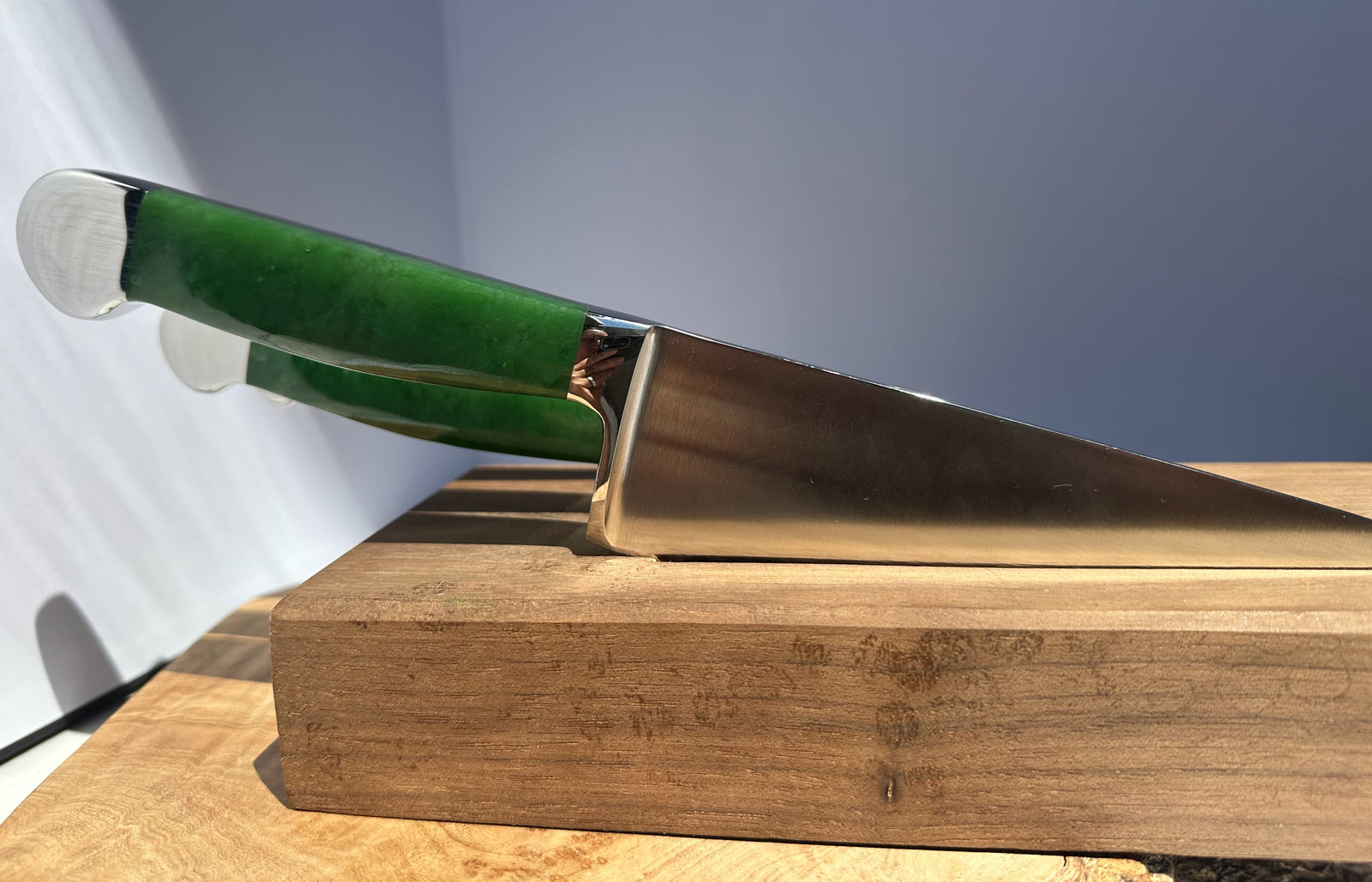 Knife with a green jade handle on a wooden block against a white background