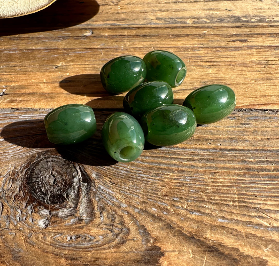Polished green jade bead measuring 12 by 15 mm with an oval shape