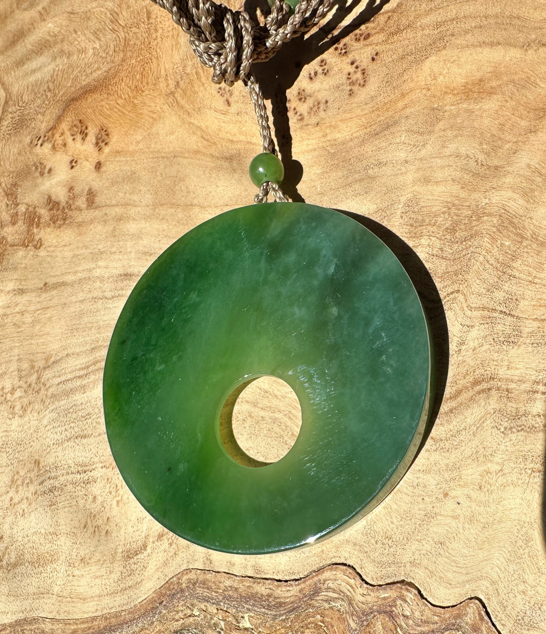 Green jade pendant on wooden base