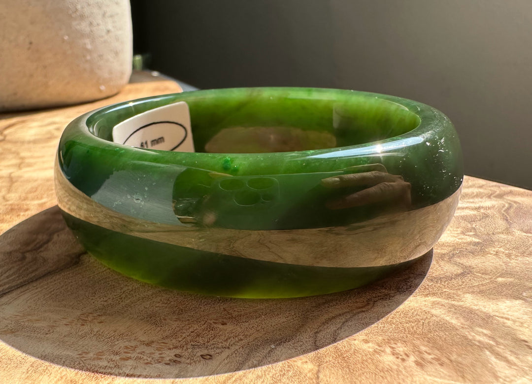 Green jade bangle with a glossy finish and a white tag inside indicating size 61 mm