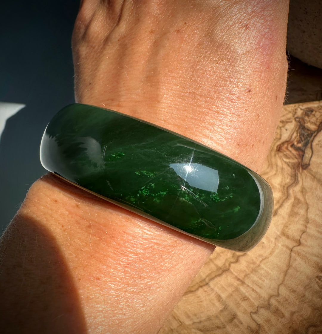 Close-up of a glossy green jade bangle on the wrist