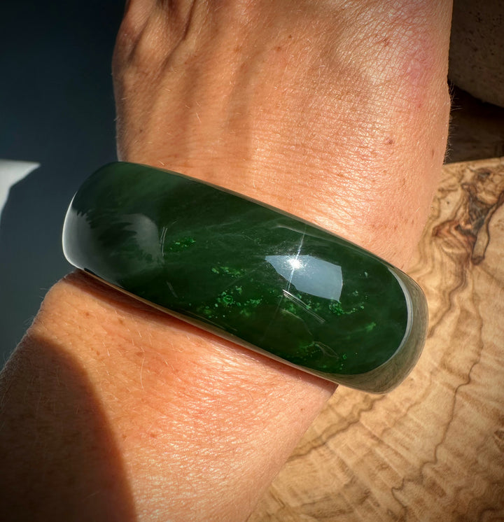 Close-up of a glossy green jade bangle on the wrist