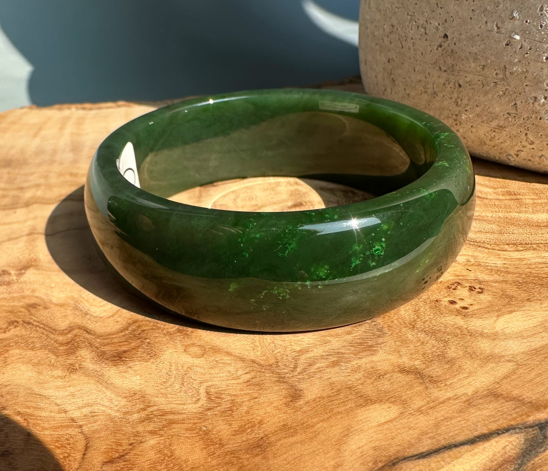 Jade bangle 61 x 22 mm worn on the wrist with a smooth glossy deep green surface