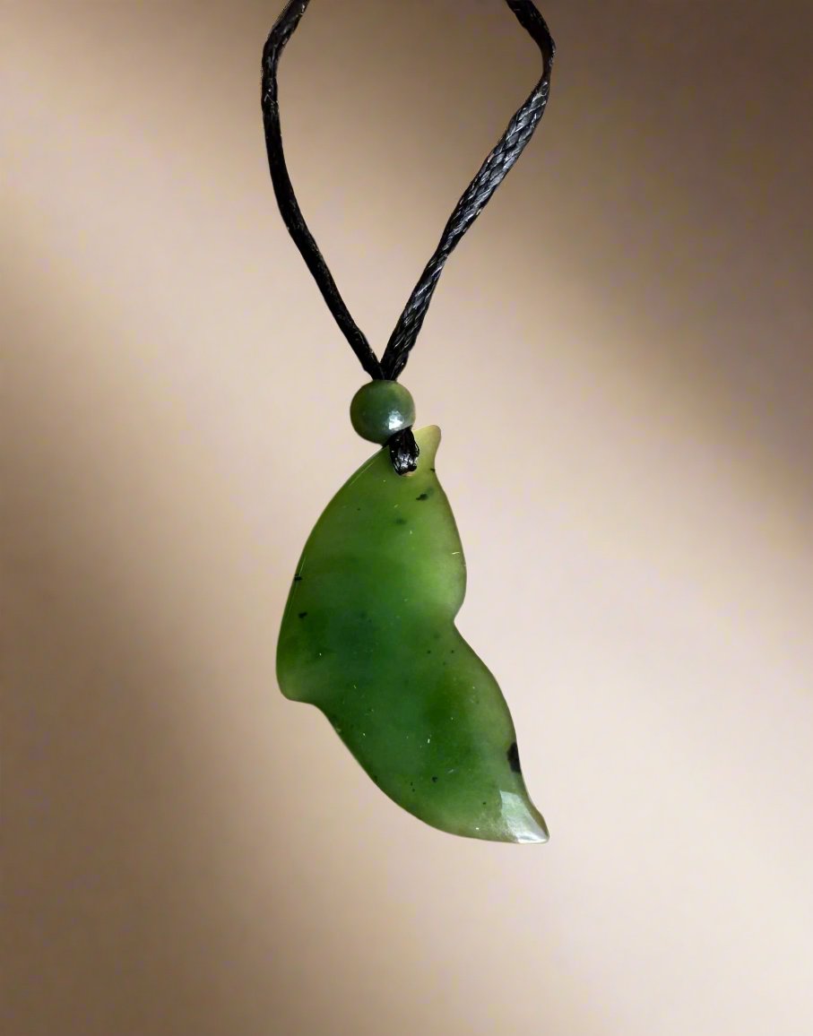 Green jade whale tail pendant on a black braided cord with a small round bead above.