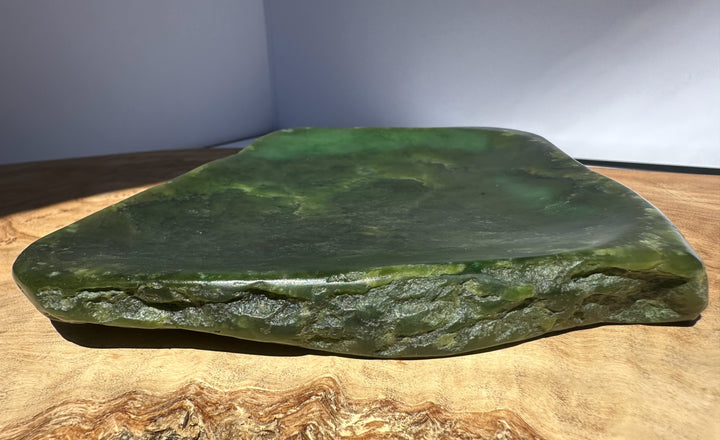 Large green stone on a wooden surface with a neutral background