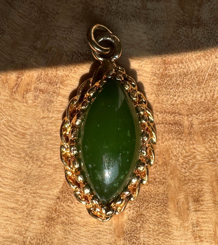 Vintage green jade marquise pendant set in an ornate gold frame and bail