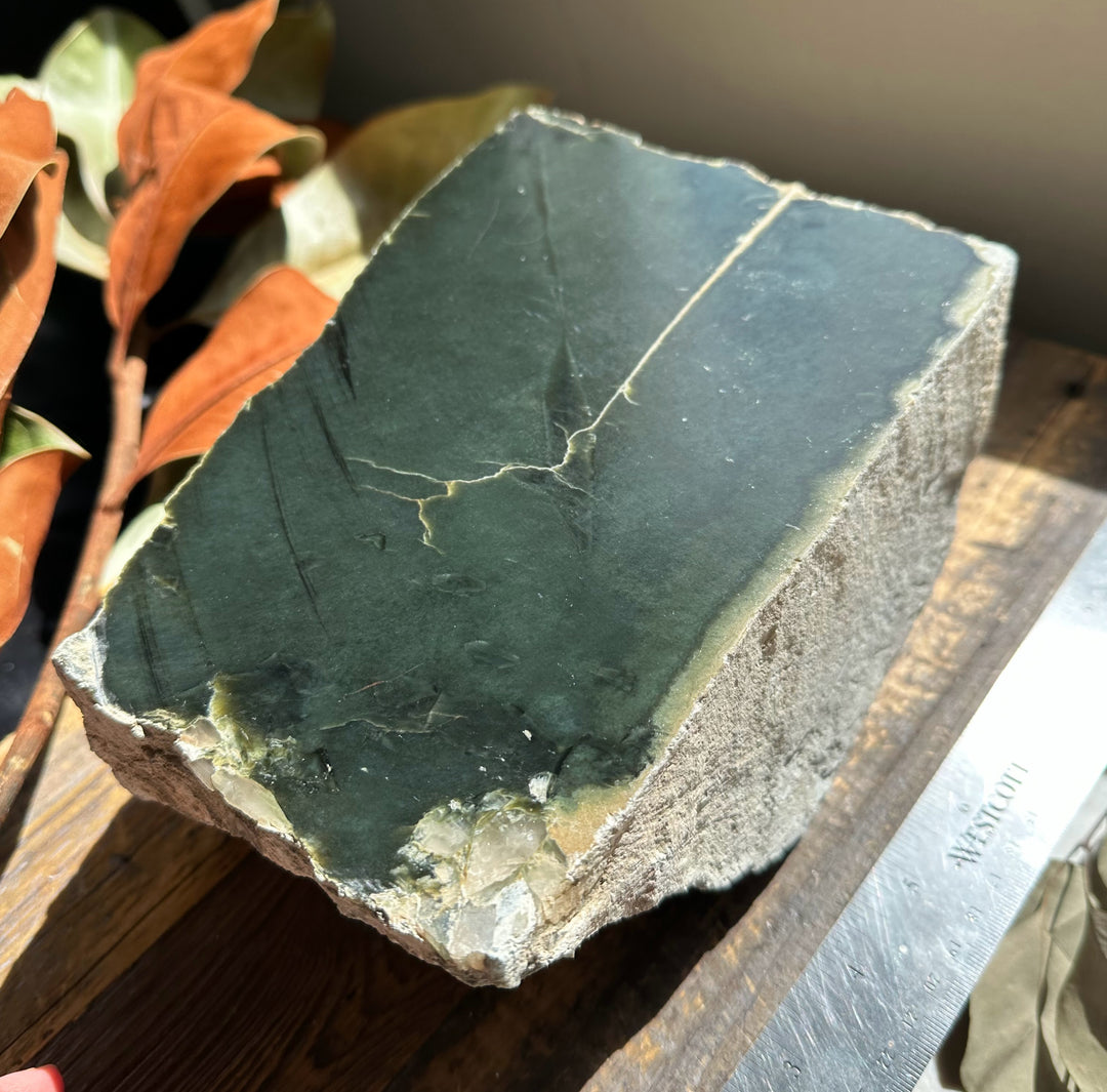Wyoming Jade slab weighing 15.4 pounds with deep green surface and visible cracks on a wooden display
