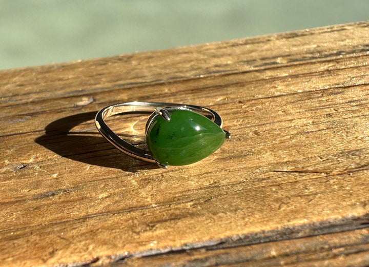 Canadian Jade and Silver Ring with a green jade cabochon on a polished silver band resting on wood