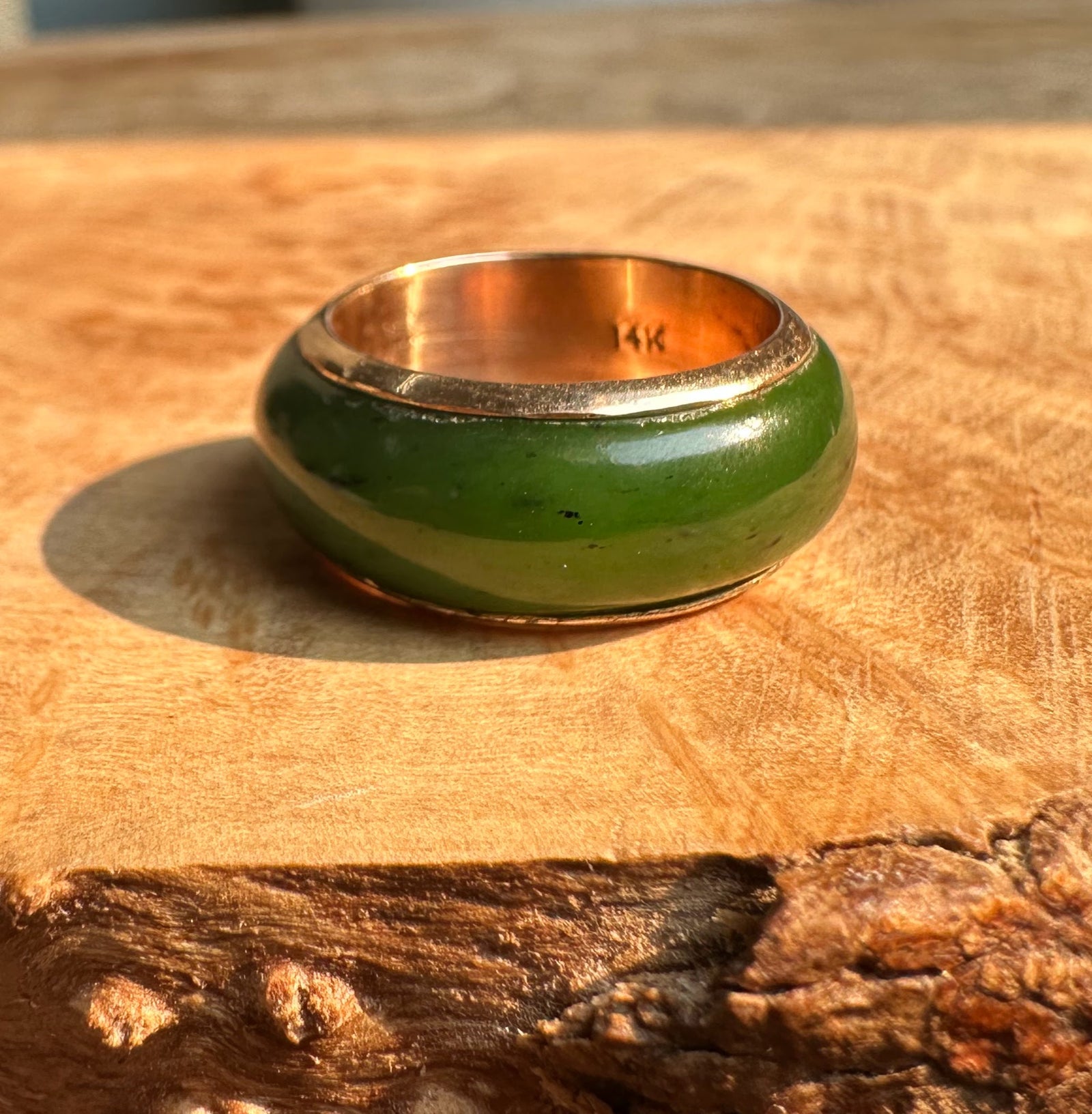 Vintage Canadian 14K ring with green enamel exterior and gold inner band on a wooden surface.