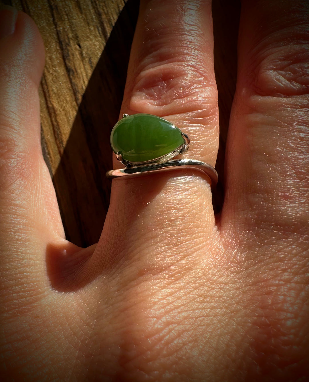Close up of a hand wearing the Canadian Jade and Silver Ring featuring a green jade stone on a silver band