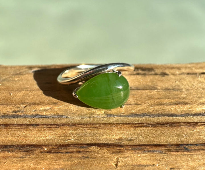 Canadian Jade and Silver Ring with a green jade cabochon set on a polished silver band atop a wooden surface