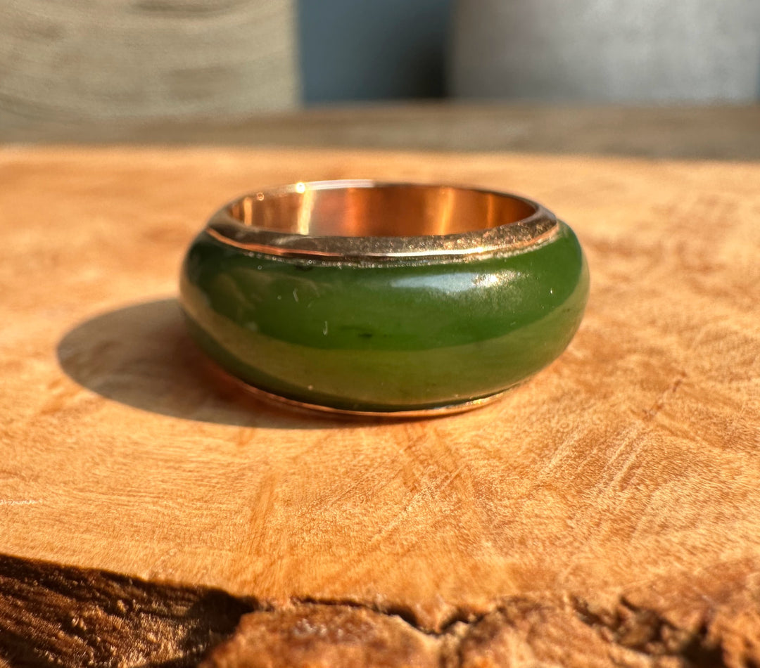 Green enamel vintage ring with 14K interior resting on a wooden surface.