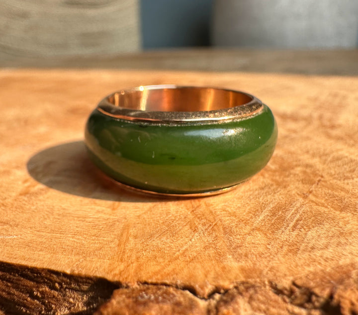 Green enamel vintage ring with 14K interior resting on a wooden surface.