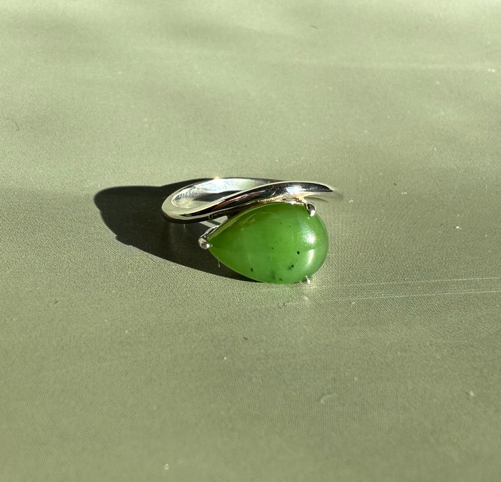 Canadian Jade and Silver Ring shown against olive satin background with a curved silver band and green jade cabochon